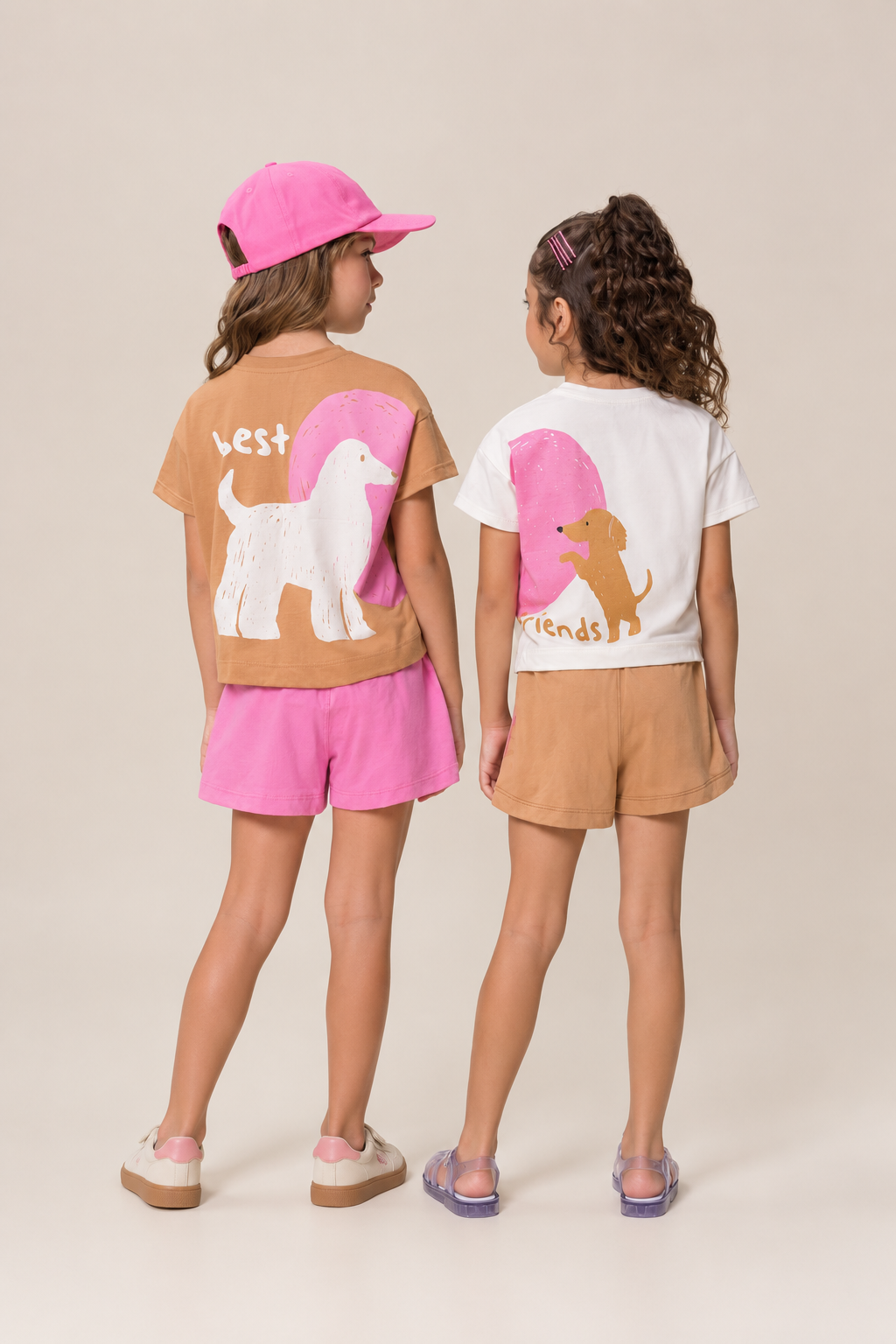 Dos niñas de espaldas con conjuntos Best Friends de Bugbee, sobre fondo beige.